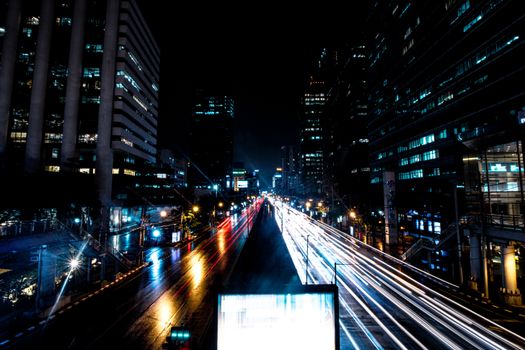 Dynamic cityscape at night featuring light trails on busy streets and illuminated skyscrapers.