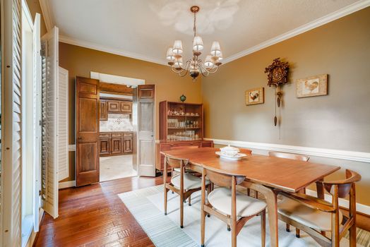 Cozy dining room with wooden furniture and chandelier, ideal for homes.