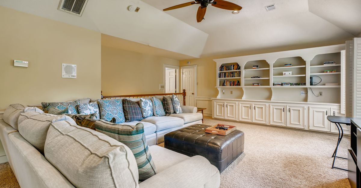 Spacious living room featuring a comfy couch and stylish shelving, perfect for relaxation.