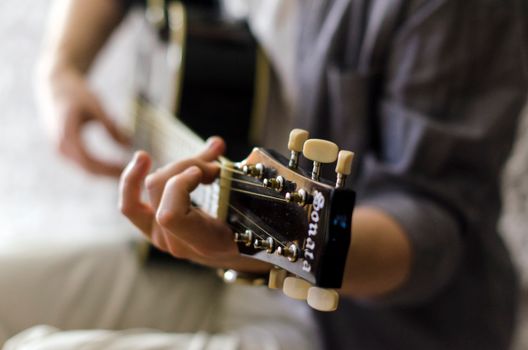 Close-up view of a guitar headstock being played, highlighting the tuning keys and strings.