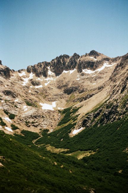 Breathtaking view of a rugged mountain with snow patches against a clear blue sky.