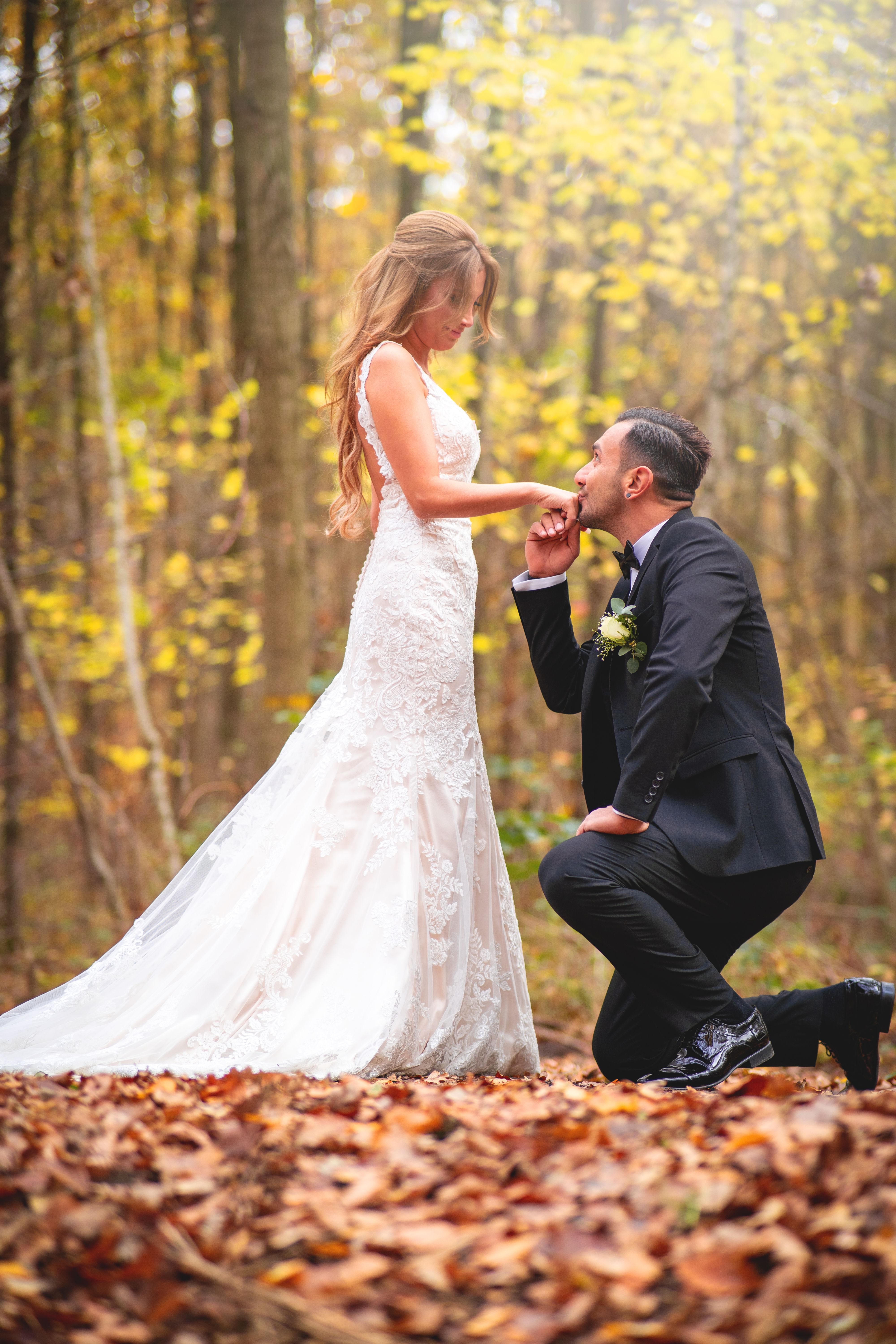 Bride and groom share a romantic moment in an autumn forest setting.