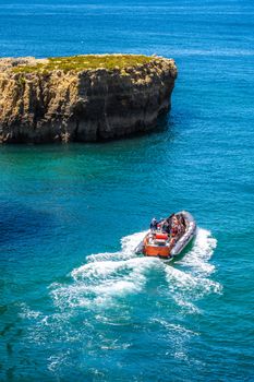 A thrilling speedboat tour navigating through the vibrant blue waters near Altura's rocky cliffs in Faro, Portugal.