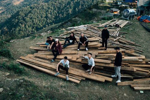 Free A diverse group sitting on timber in a rural area surrounded by lush greenery. Stock Photo