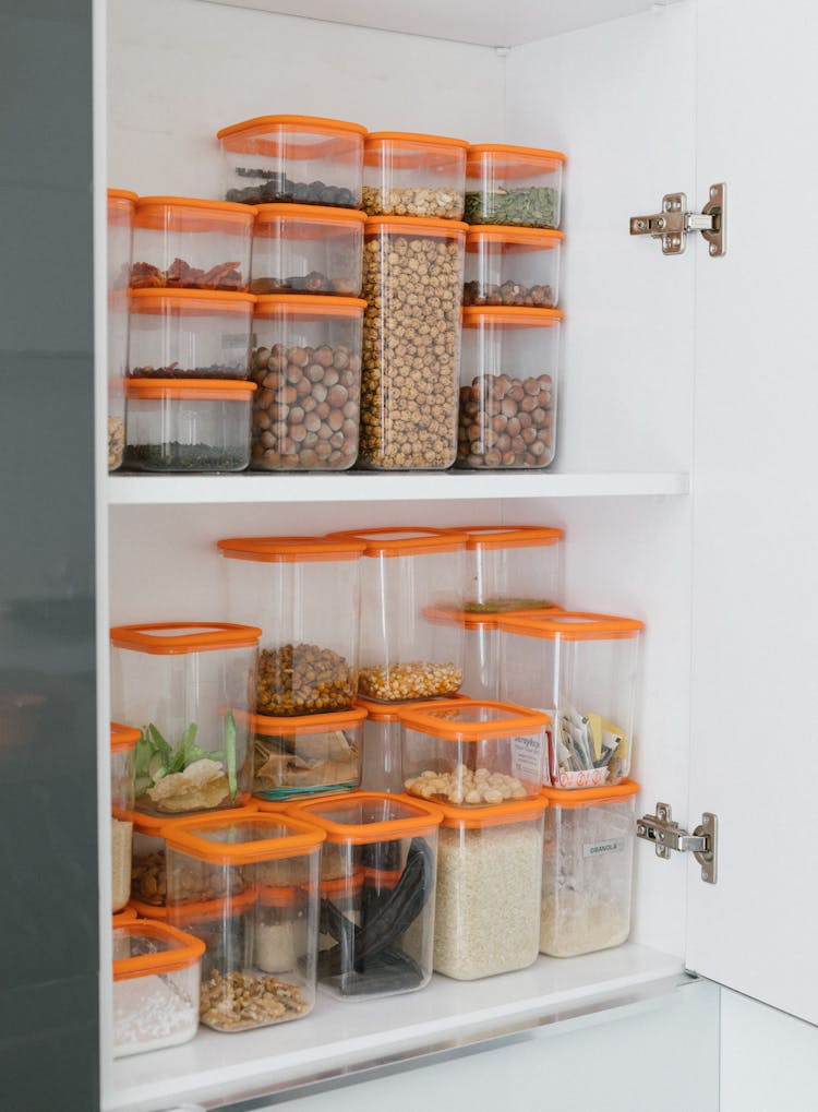 Clear Plastic Containers With Assorted Nuts And Grains On White Shelf