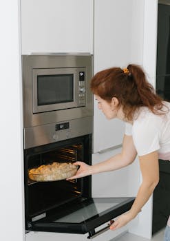 Woman placing pie in oven in a modern Istanbul kitchen.