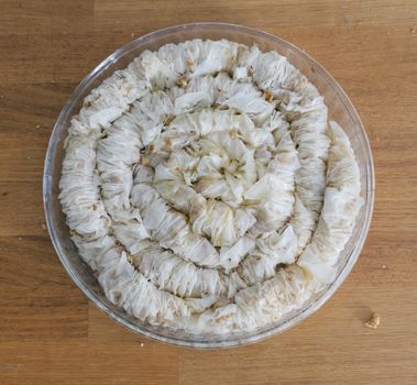 A top-down view of homemade rolled baklava in a glass bowl, showcasing Turkish pastry art.