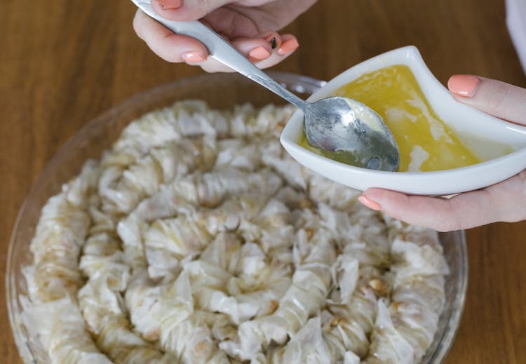 A Person Scooping Melted Butter With A Spoon