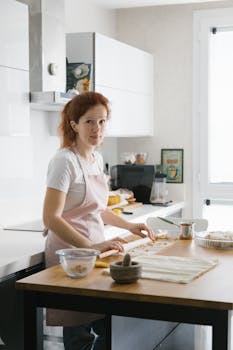 A woman in a kitchen prepares homemade pastry, showcasing a cozy domestic scene.
