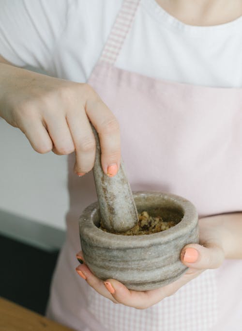 A Close-Up Shot of a Person Using a Mortar and Pestle