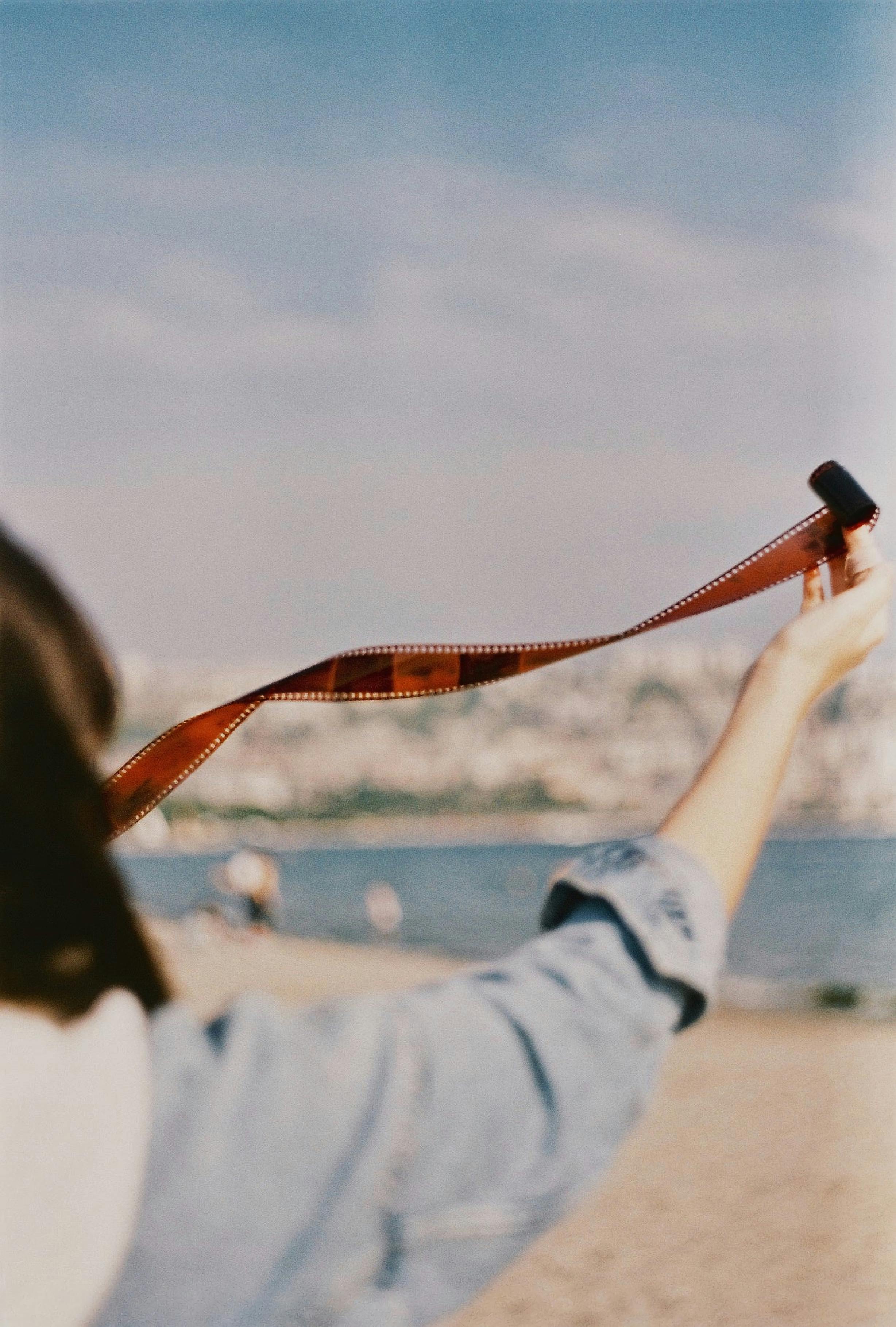 Person holding film strip on Istanbul beach, evoking nostalgia and travel vibes.