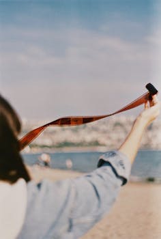 Person holding film strip on Istanbul beach, evoking nostalgia and travel vibes.