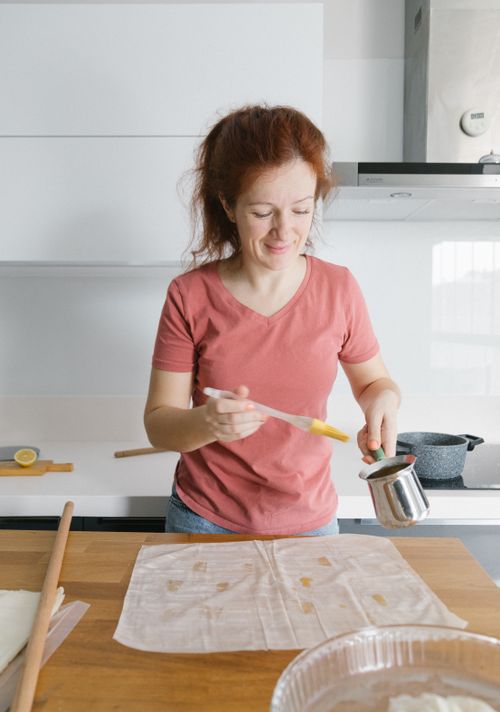 Free Woman with red hair making dough in a bright, modern kitchen setting in Istanbul. Stock Photo