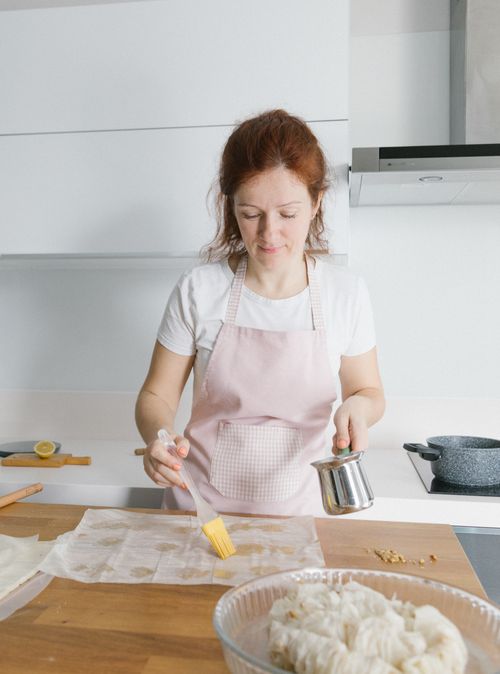 Free A woman in a pink apron prepares pastries in a modern Istanbul kitchen. Stock Photo