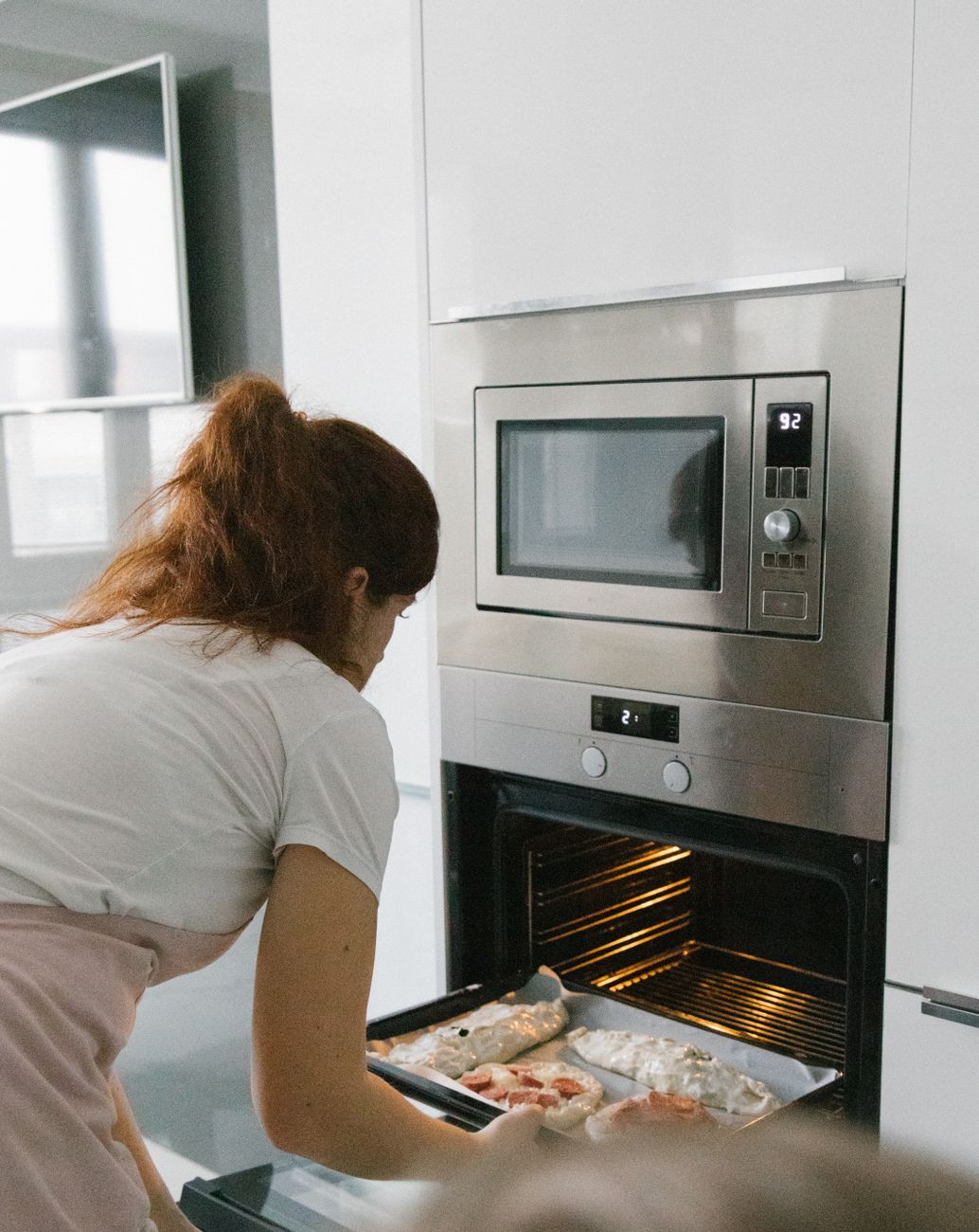 A tray sliding into a modern oven in a bright home kitchen