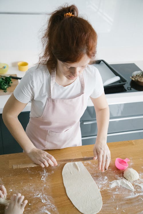 High-Angle Shot of a Woman Flattening a Dough with a Thin Rolling Pin