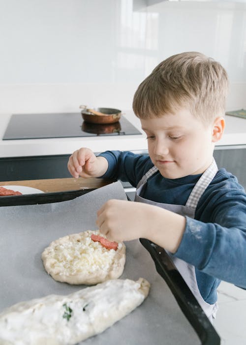 Boy in Blue Long Sleeve Shirt Putting Meat on Dough