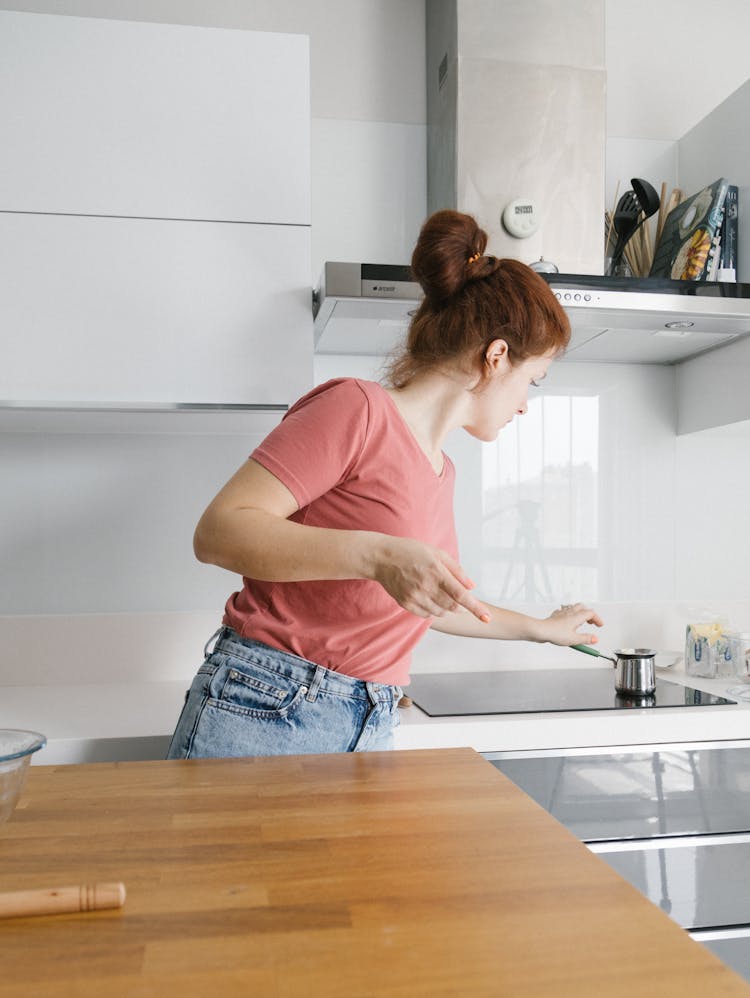 A Woman In Pink Shirt Reaching For A Stainless Cup