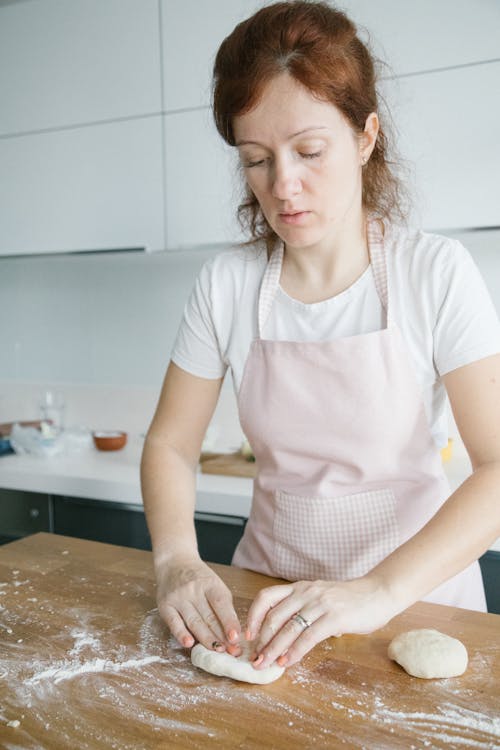 Woman Wearing an Apron Kneading a Dough