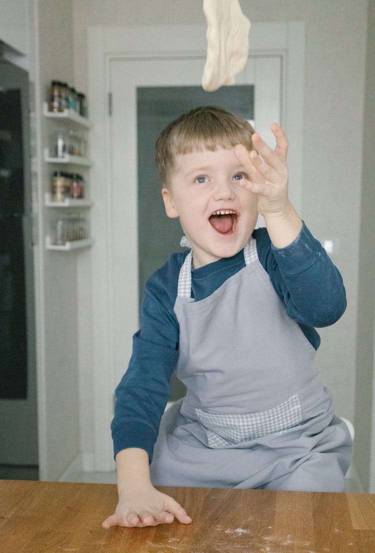 Boy In Blue Long Sleeve Flipping A Dough