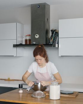 A woman preparing food in a modern Istanbul kitchen, focused on her baking task.
