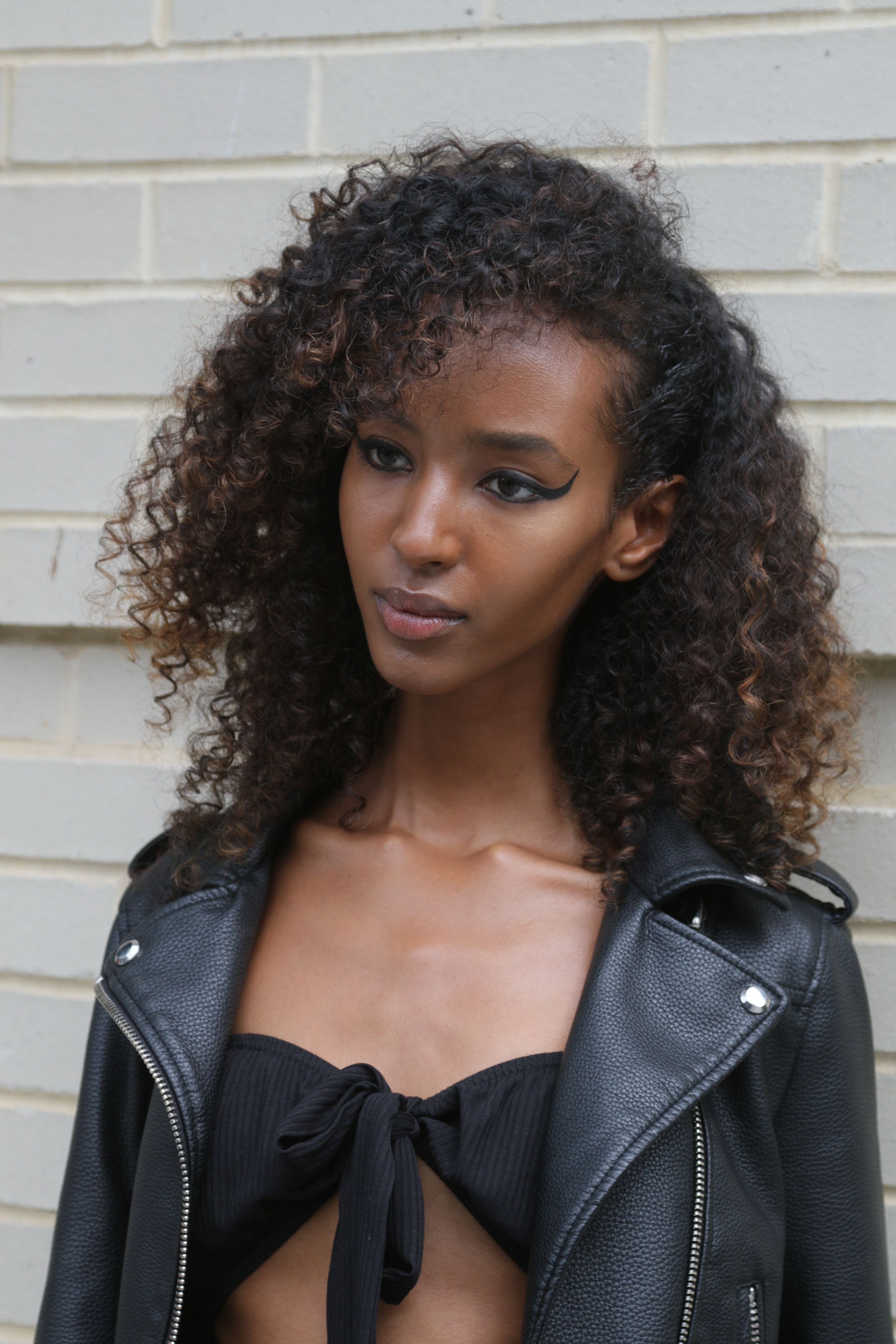 Elegant portrait of a young woman in a black leather jacket, showcasing urban fashion.