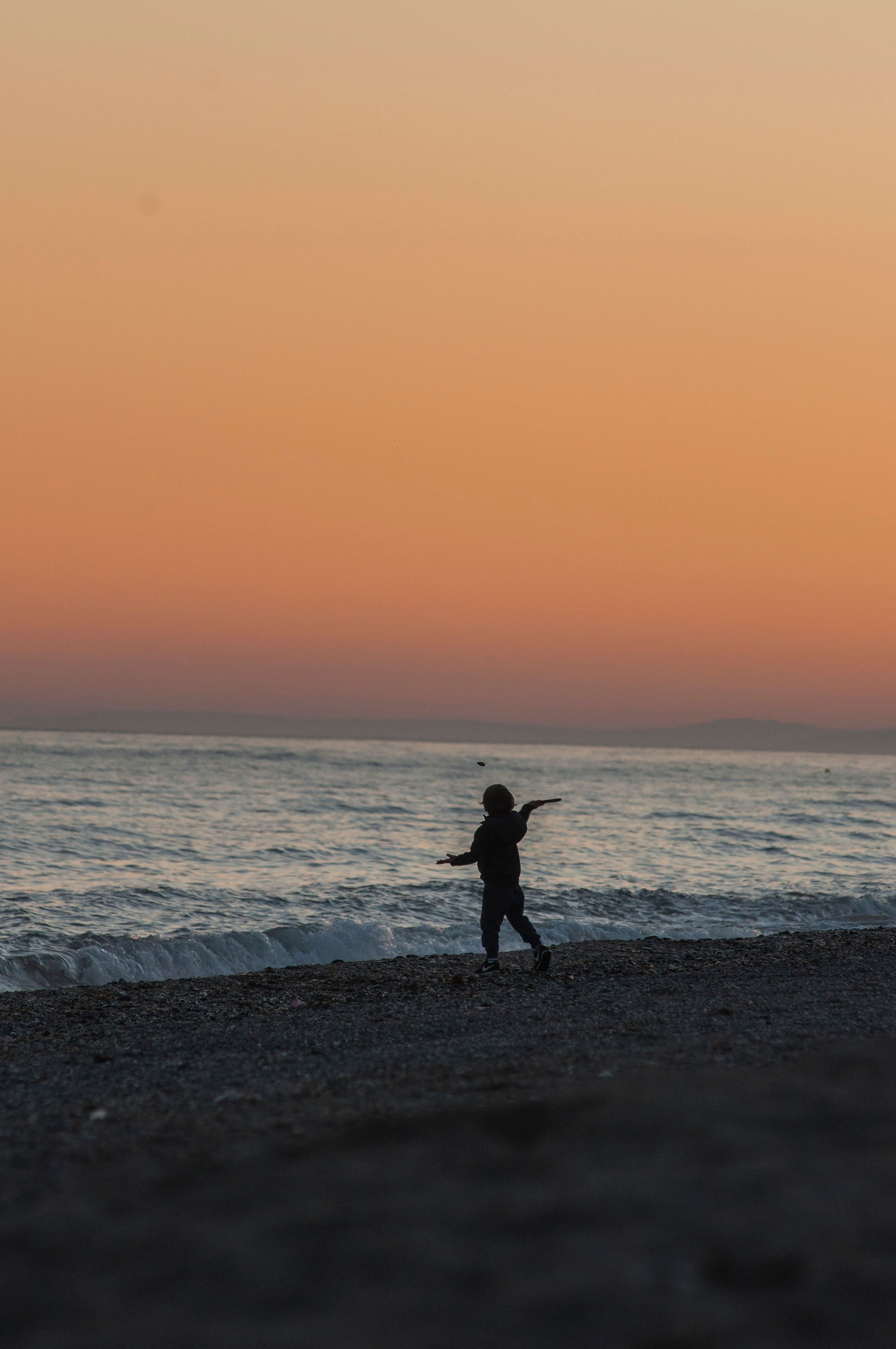 Silhouette of a Person Standing on the Beach · Free Stock Photo