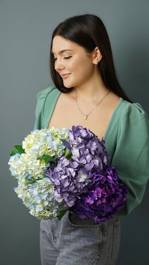 A Woman Holding Clusters of Hydrangea Flowers