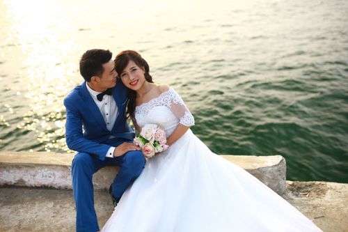Free Elegant Asian couple in wedding attire by a serene lake, capturing a moment of love. Stock Photo