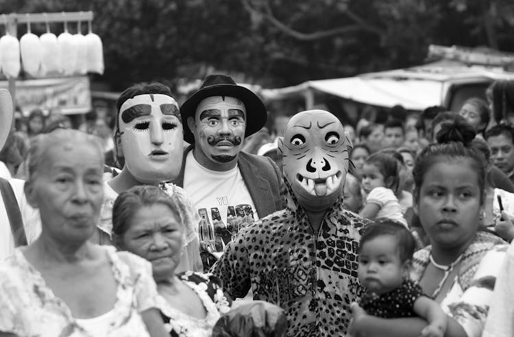 Grayscale Phot Of People Wearing Masks In A Crowd 