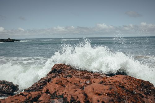 Free Powerful ocean waves crash against a rugged rocky shoreline under a bright sky. A vivid display of nature's force. Stock Photo