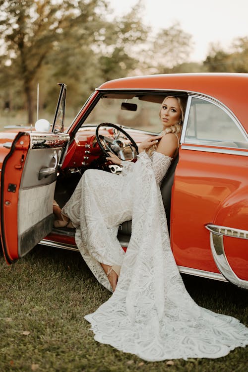 A Woman in Her Wedding Dress Sitting in a Vintage Car