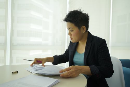 Free Businesswoman reviewing documents at a round table in a bright office space. Stock Photo