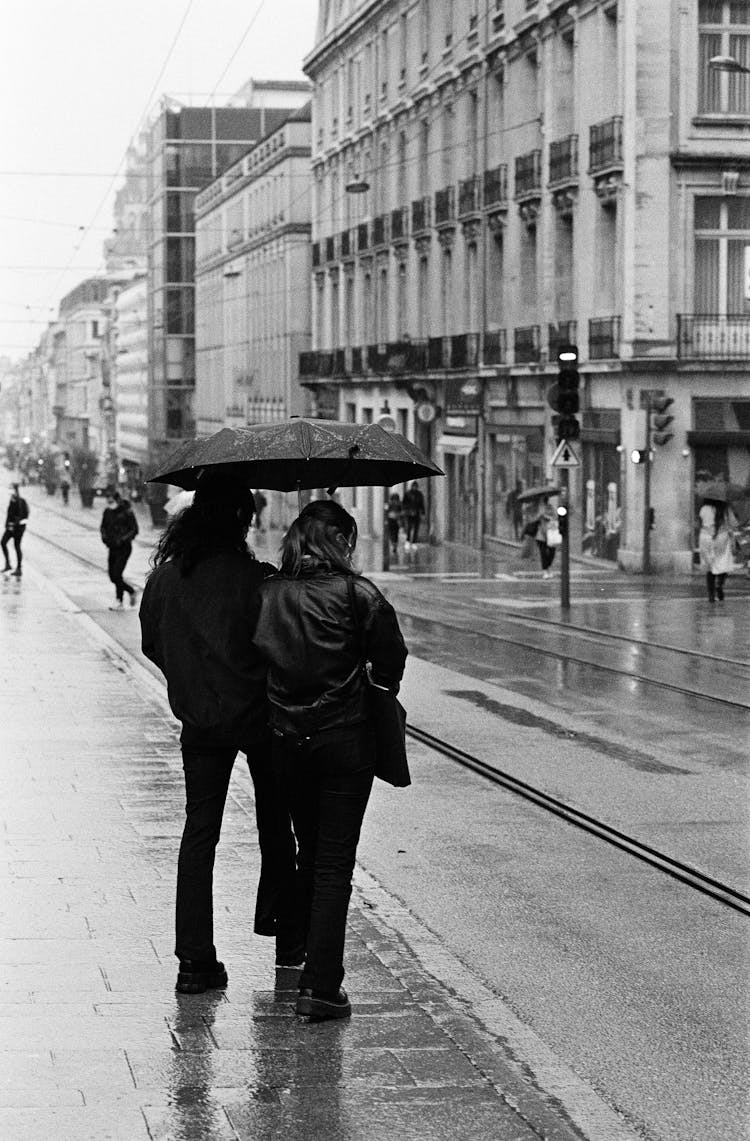 Backside Of A Couple Sharing An Umbrella