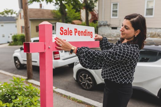 Realtor adjusting a 'Sale Pending' sign on a sunny day in a residential area.