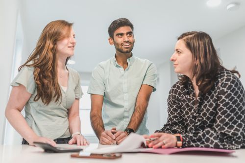 Free Three diverse adults conversing happily about real estate in a bright indoor setting. Stock Photo