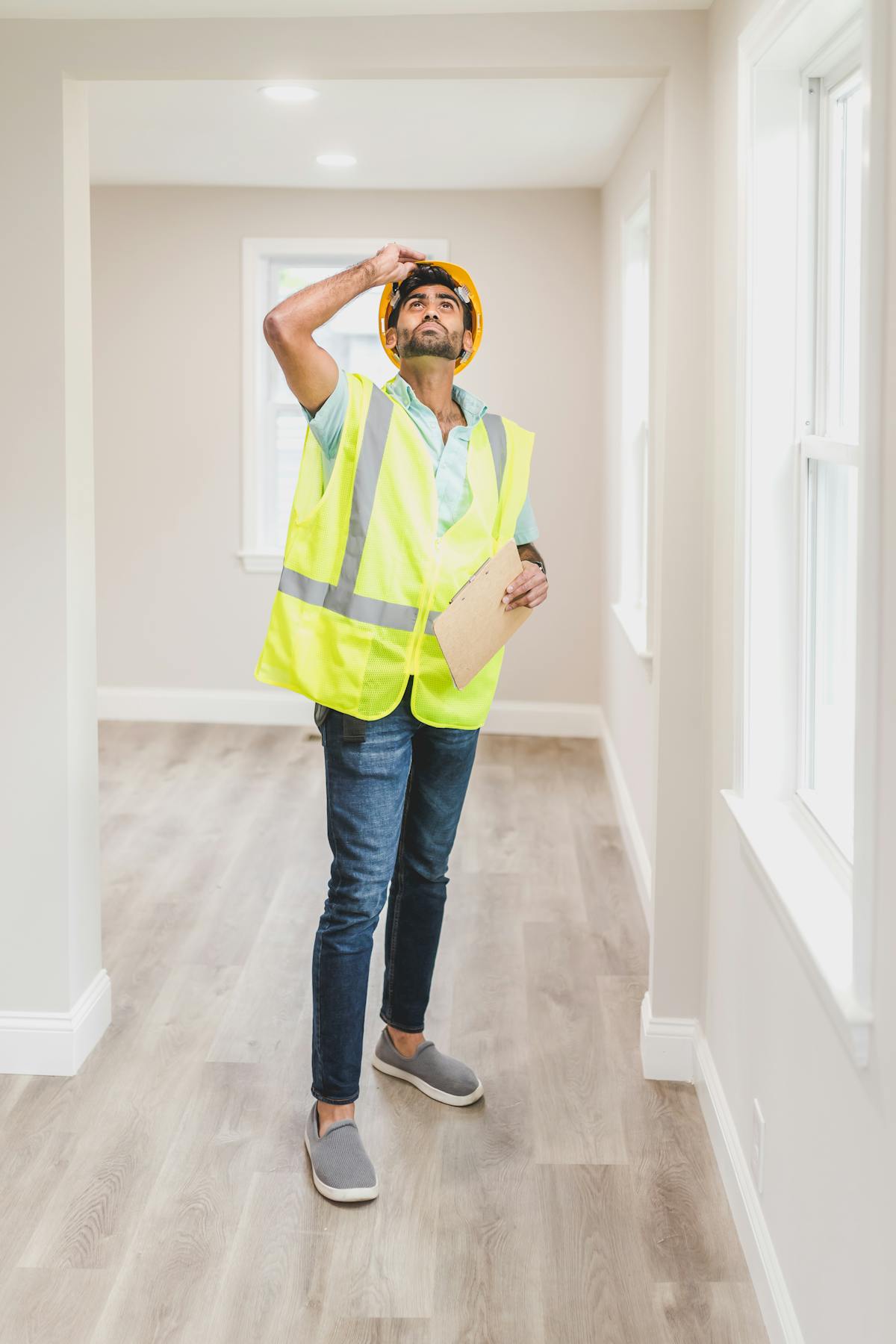 Construction inspector in a safety vest and hard hat examining an empty house interior