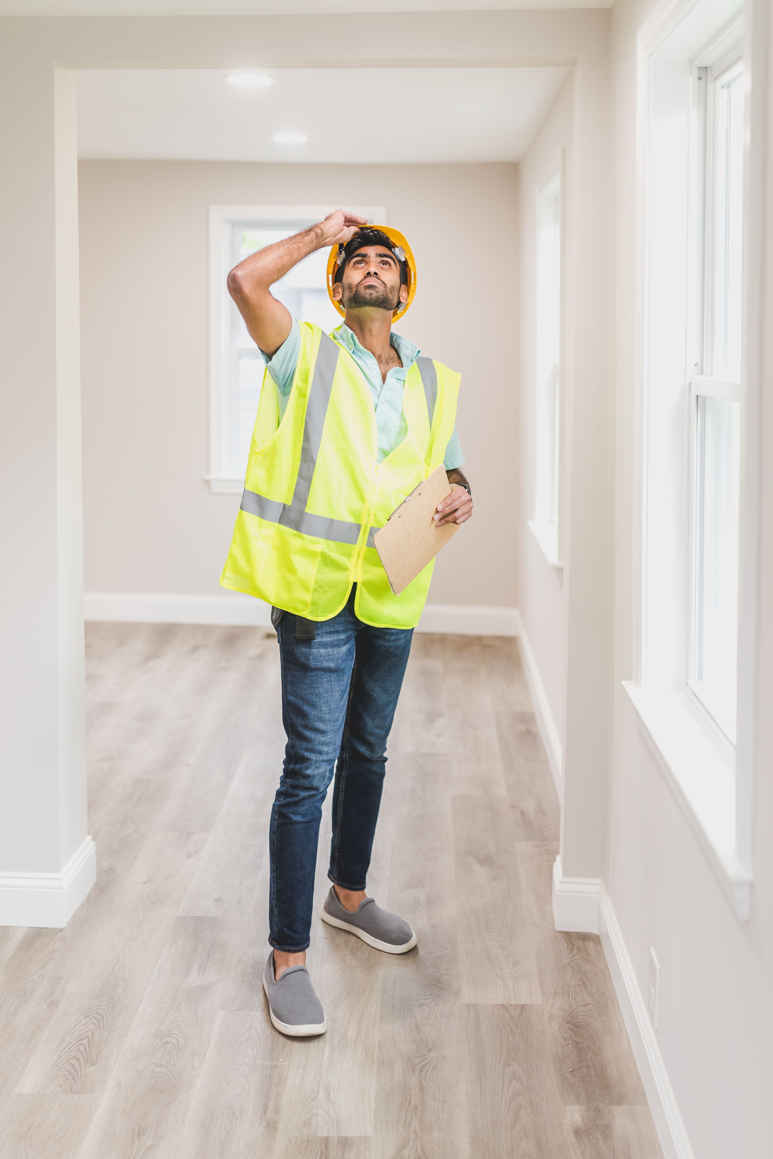 A contractor in a safety vest inspecting the interior of an empty house before a home sale