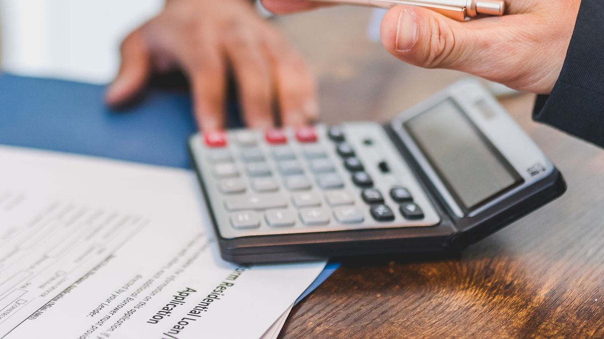 Pessoa fazendo contas com calculadora sobre documentos