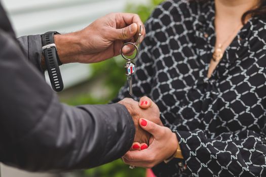 A close-up shot of hands exchanging a house key, symbolizing real estate transactions or new home ownership.