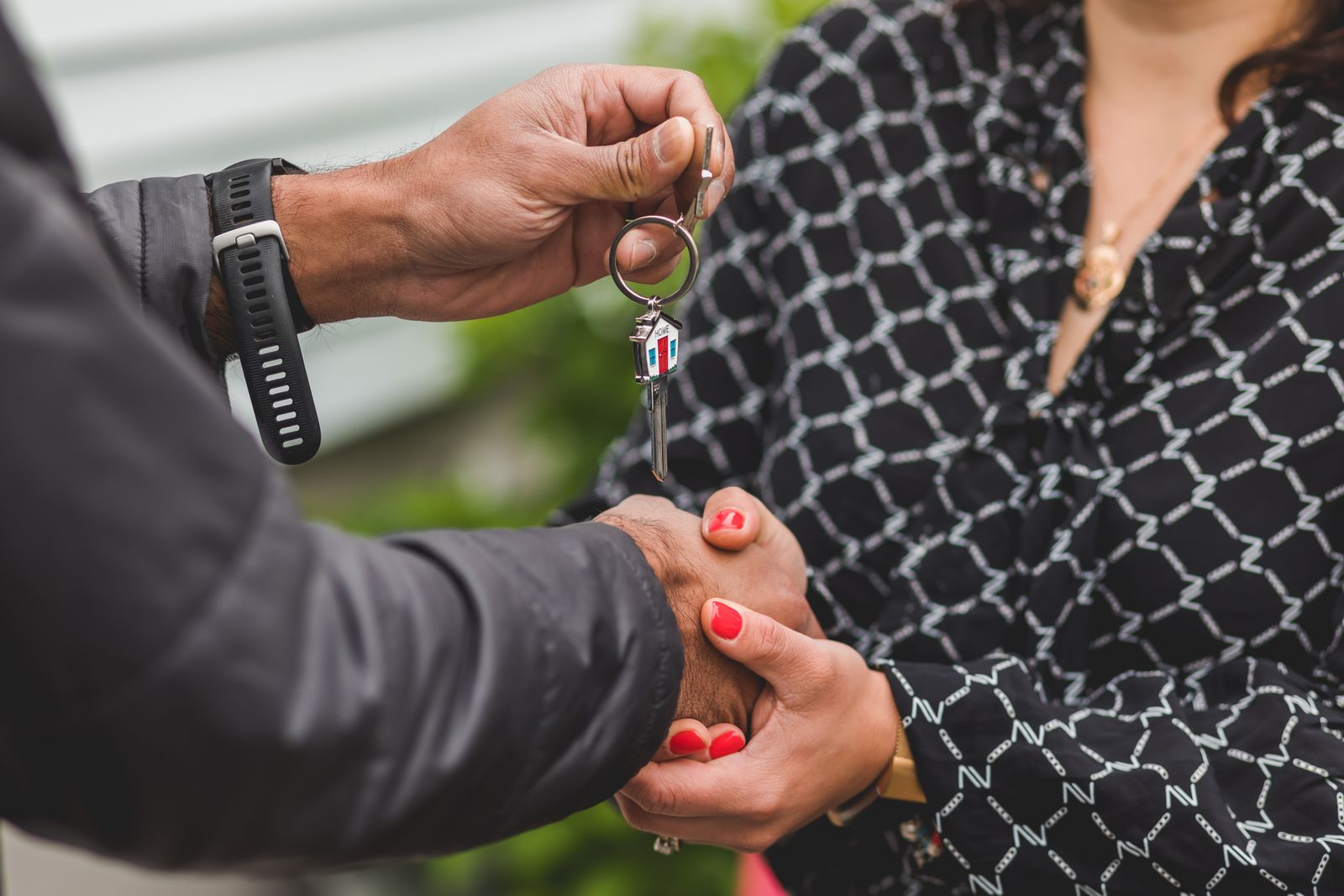 Free A close-up shot of hands exchanging a house key, symbolizing real estate transactions or new home ownership. Stock Photo