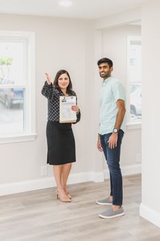 Agent shows house to potential buyer, highlighting features in bright interior.