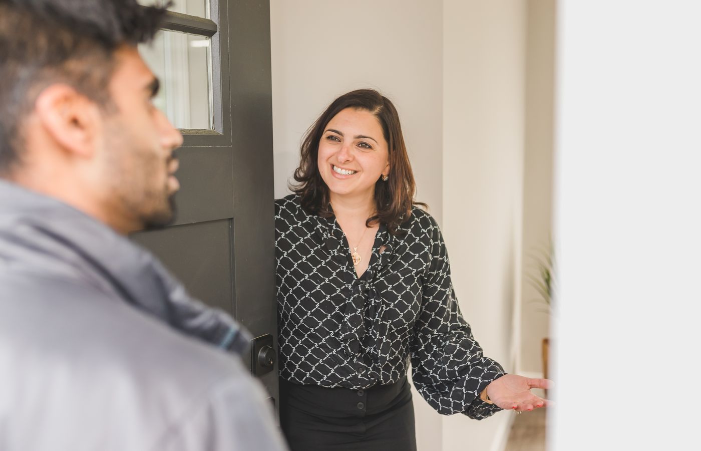 Friendly real estate agent greets client at the door, showcasing modern hospitality.