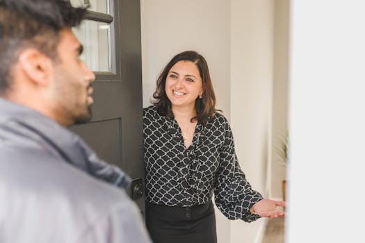Friendly real estate agent greets client at the door, showcasing modern hospitality.
