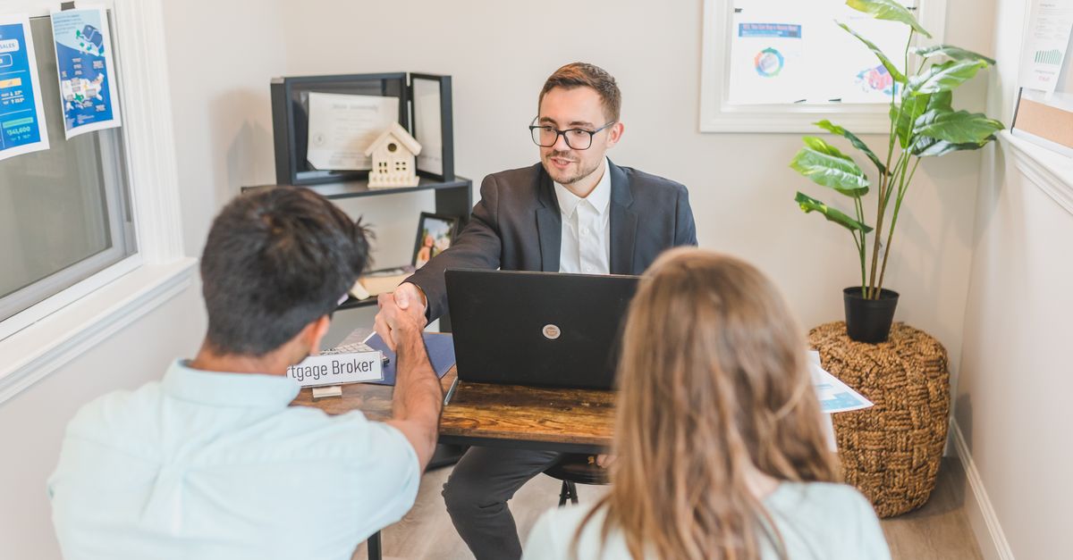 Men and woman discussing mortgage with broker in a modern office setting.