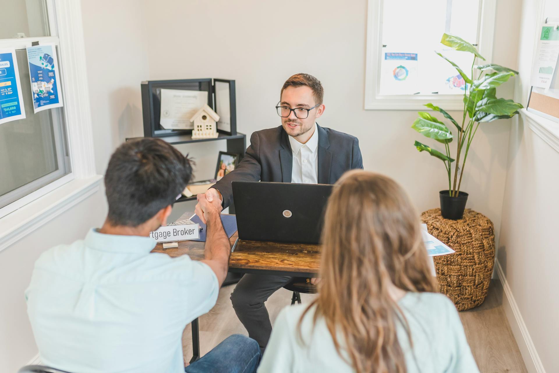 Men and woman discussing mortgage with broker in a modern office setting.