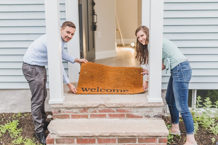 A Couple Holding A Welcome Mat