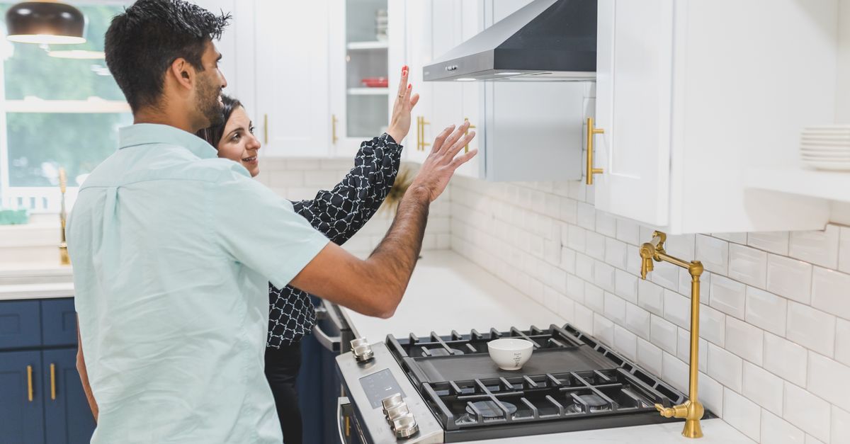 A real estate agent demonstrates kitchen features in a modern home. Ideal for real estate and lifestyle concepts.