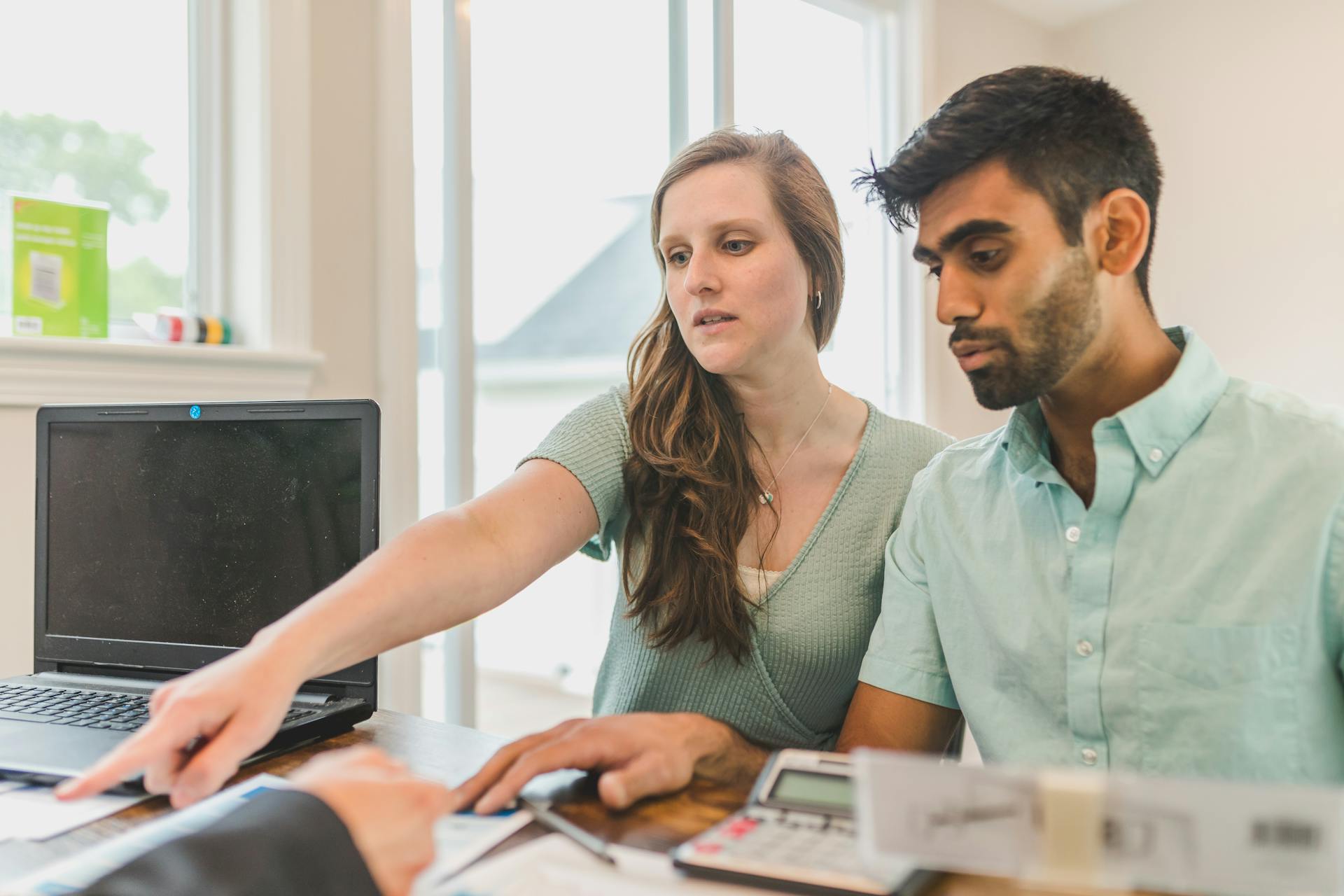 A young couple reviewing real estate documents with an advisor in a bright office.