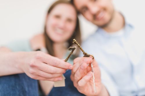Free Smiling couple celebrates new home purchase, gripping vintage keys with love and excitement. Stock Photo